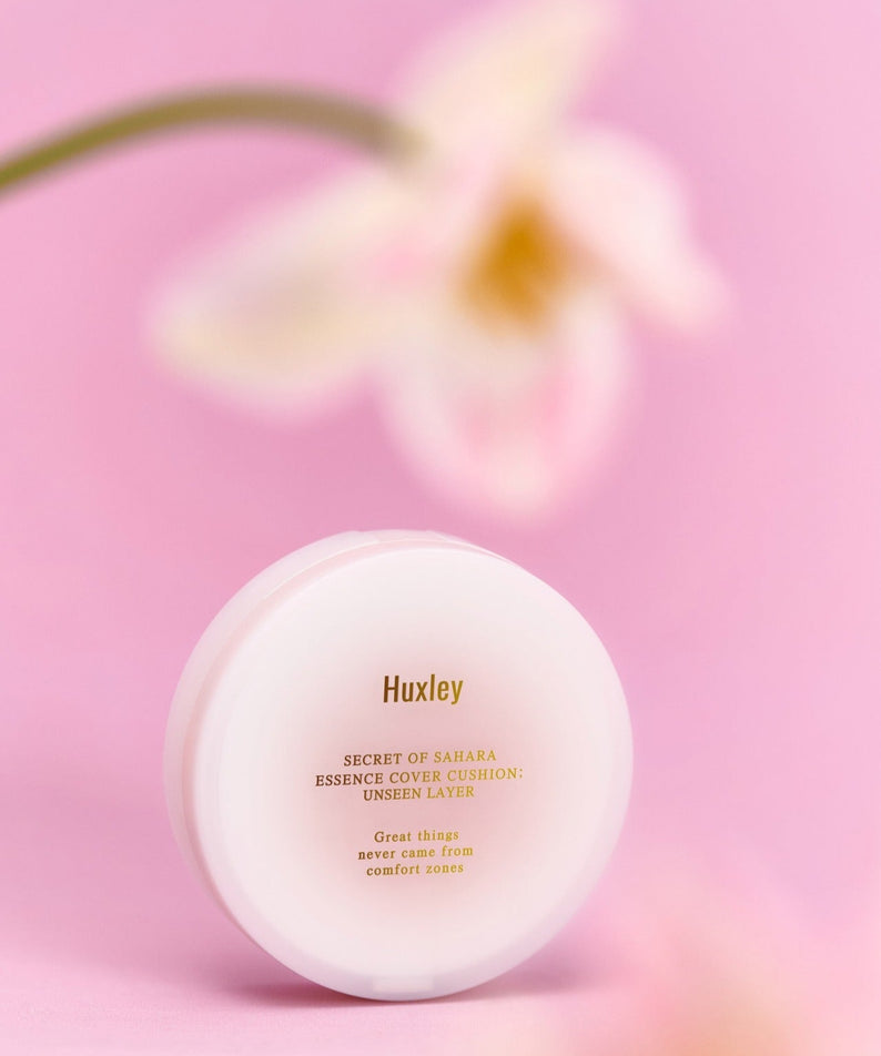 Coussin HUXLEY Essence Cover Cushion Unseen Layer sur fond rose, accentuant la beauté naturelle et le teint uniforme en un seul geste.