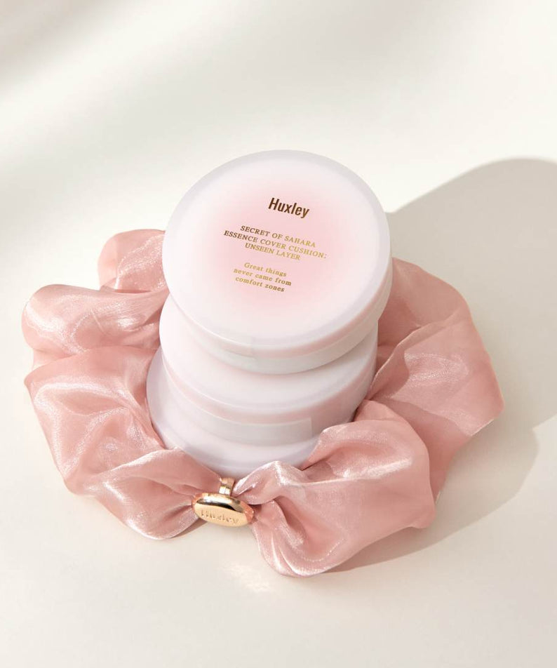HUXLEY Essence Cover Cushion Unseen Layer présenté avec élégance sur une étoffe rose, idéal pour un teint naturellement parfait.