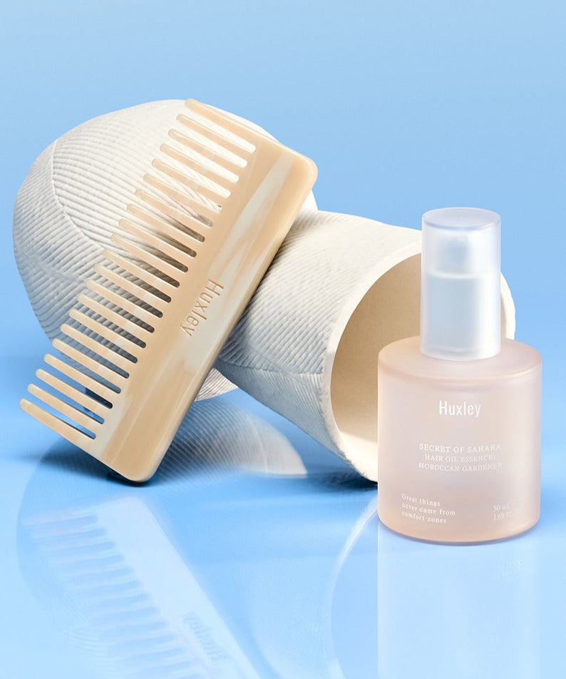 HUXLEY Hair Oil Essence Moroccan Gardener 50ml : flacon Huxley et peigne sur fond bleu, huile capillaire de soins.
