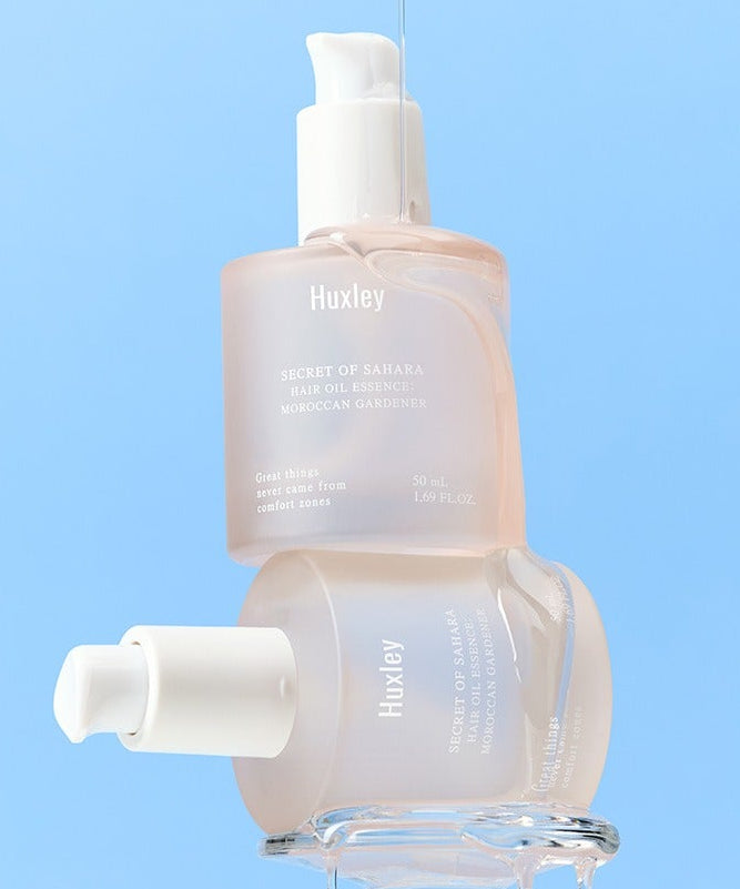 HUXLEY Hair Oil Essence Moroccan Gardener 50ml, flacon sur fond bleu, huile capillaire marque Huxley en contexte visuel