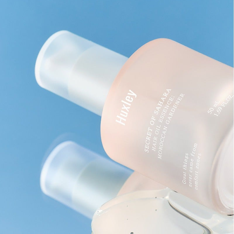 HUXLEY Hair Oil Essence Moroccan Gardener 50ml, flacon sur fond bleu, huile capillaire HUXLEY en contexte visuel beauté