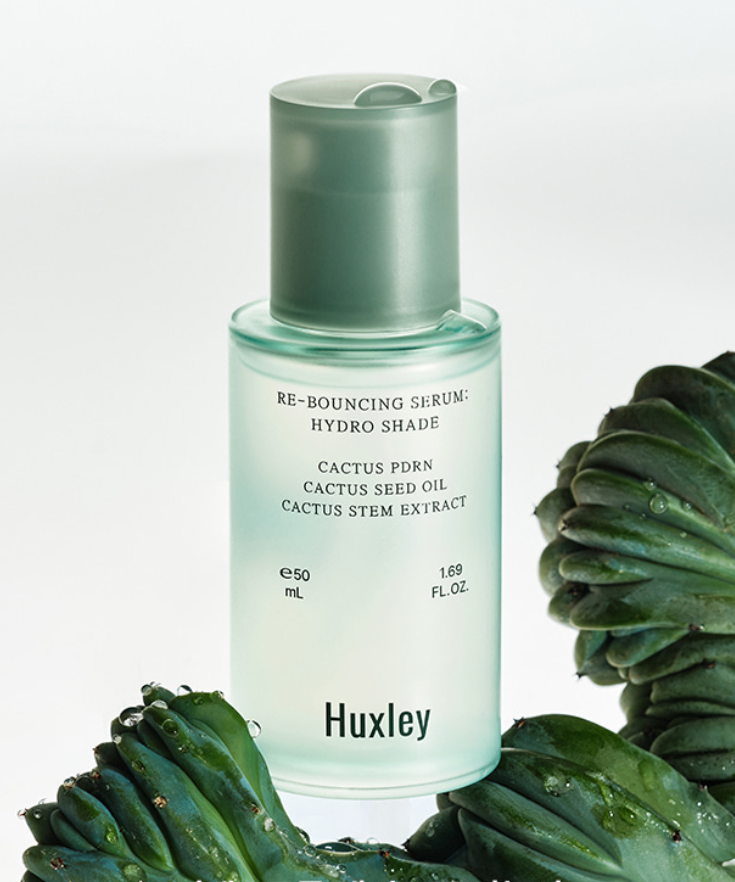 HUXLEY Rebouncing Serum Hydro Shade 50ml : flacon vert sur fond clair, plantes de cactus et feuilles, contexte beauté