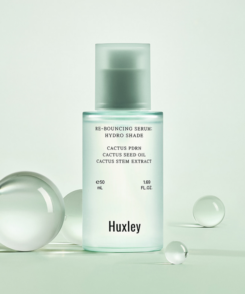 Décris l'image en français : HUXLEY Rebouncing Serum Hydro Shade 50ml de la marque Huxley, flacon sur fond vert clair.