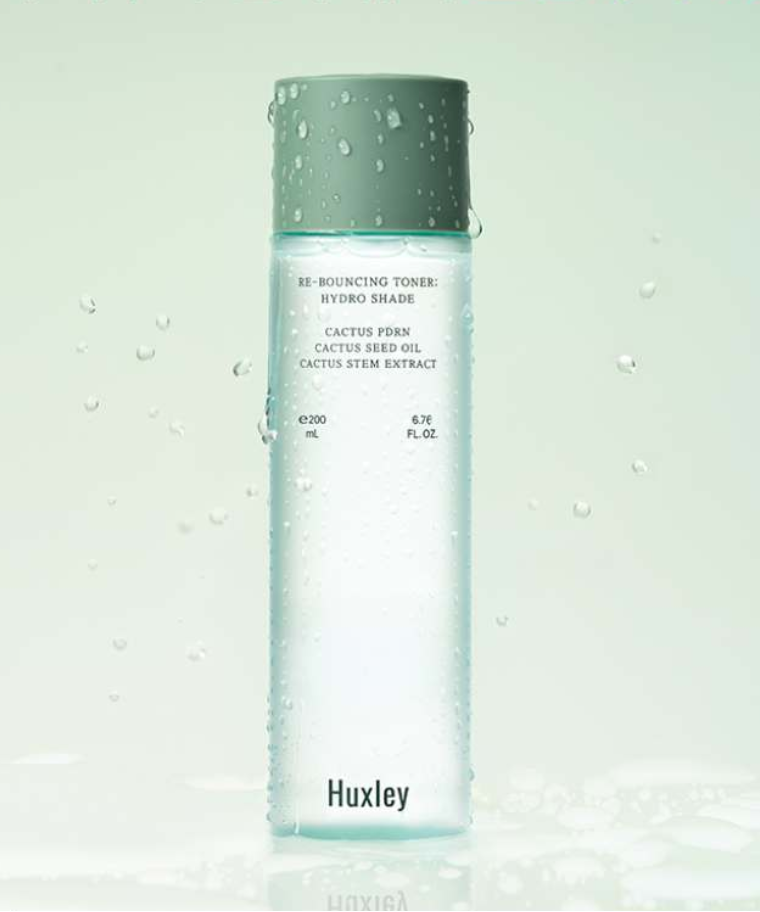 HUXLEY Rebouncing Toner Hydro Shade 200ml de Huxley, bouteille verte, gouttes d’eau sur fond clair, visuel skincare.