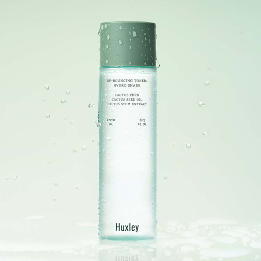HUXLEY Rebouncing Toner Hydro Shade 200ml de Huxley, bouteille verte, gouttes d’eau sur fond clair, visuel skincare.