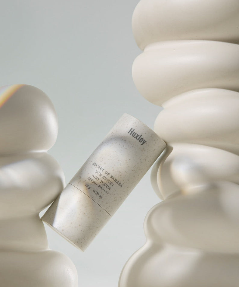 HUXLEY Sun Stick Airy Touch 20g de Huxley, pot de crème solaire posé sur un décor minimal blanc.