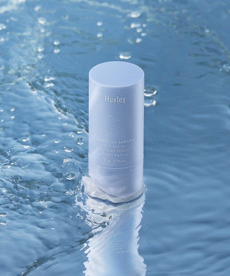 HUXLEY Sun Stick Watery Touch 20g, stick solaire Huxley sur l’eau bleue et éclaboussures, visuel rafraîchissant