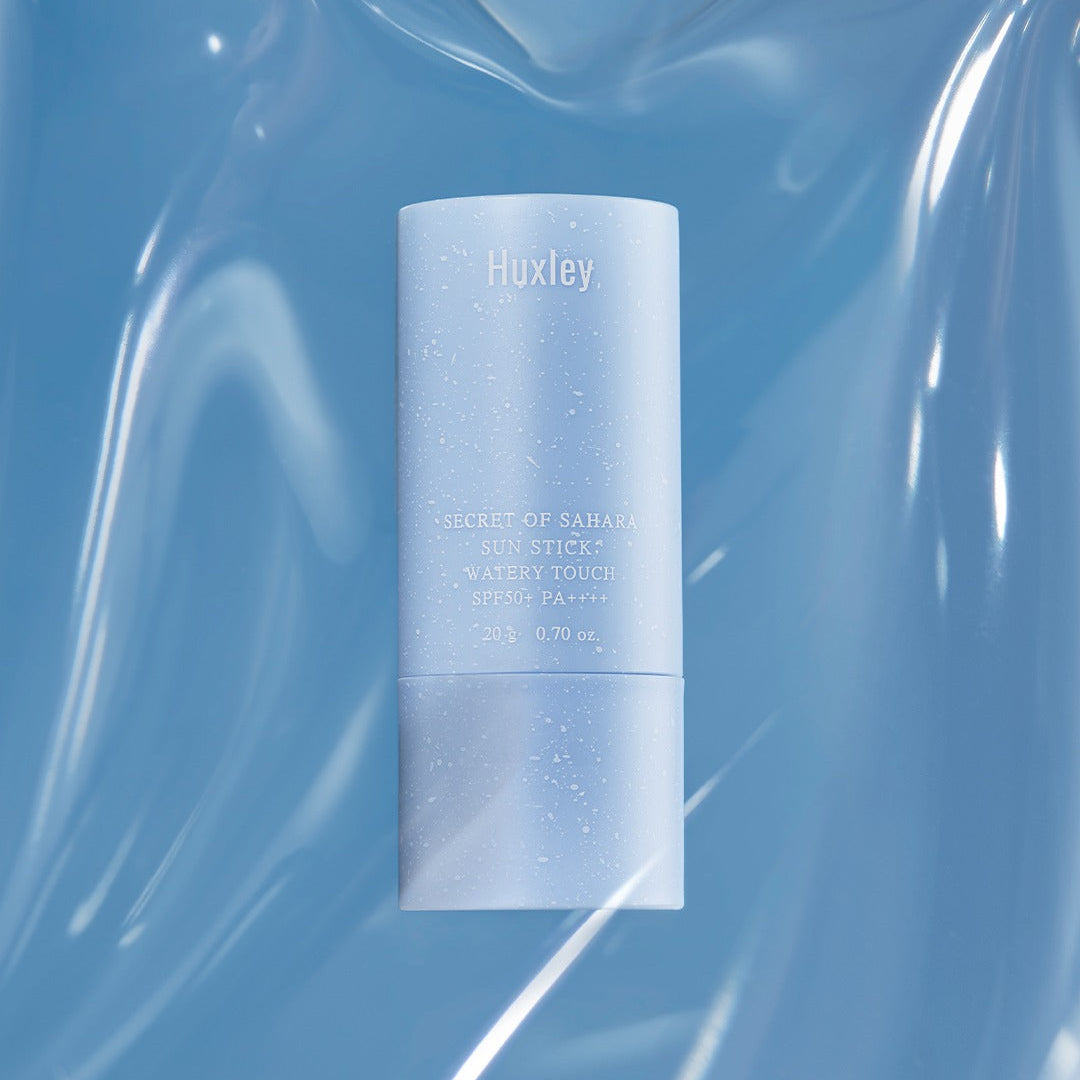 HUXLEY Sun Stick Watery Touch 20g, stick solaire Huxley sur fond bleu lumineux, contexte visuel cosmétique.