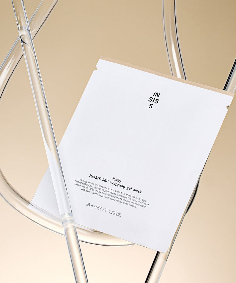 Masque en gel HUXLEY BioSIS 360 Wrapping 35g sur une chaise transparente.