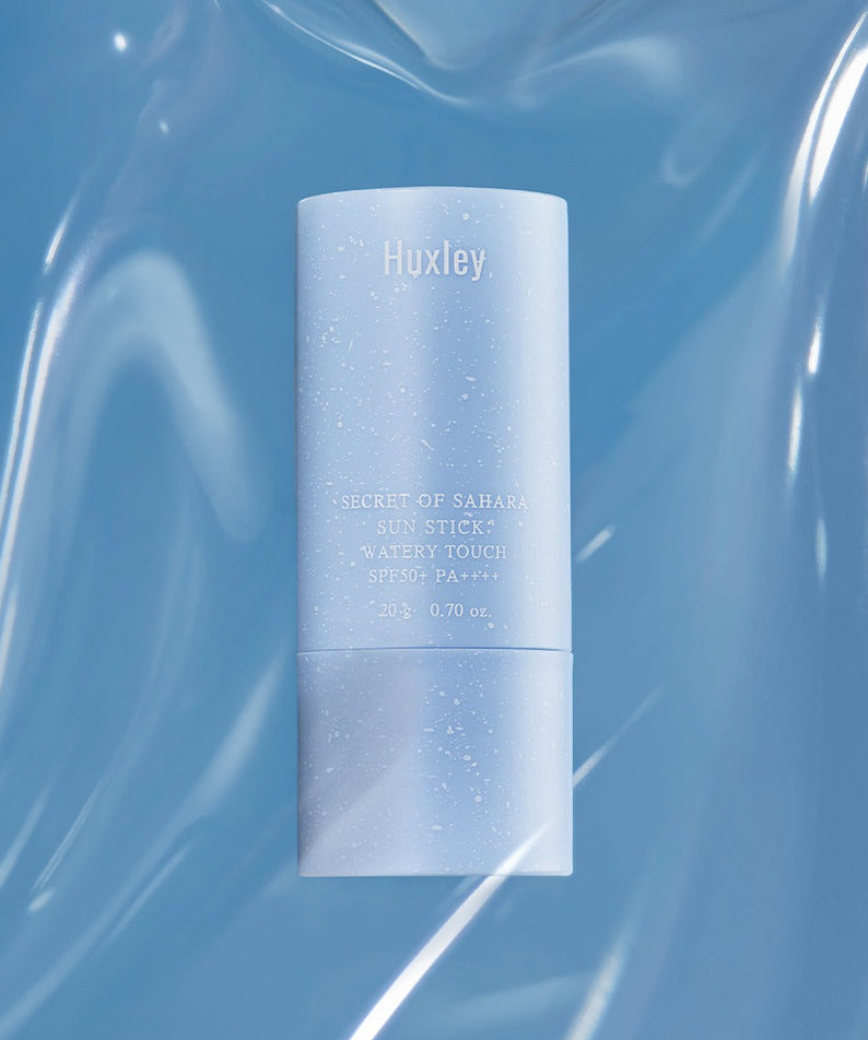 HUXLEY Sun Stick Watery Touch 20g sur fond bleu, protection solaire hydratante et légère, design élégant.