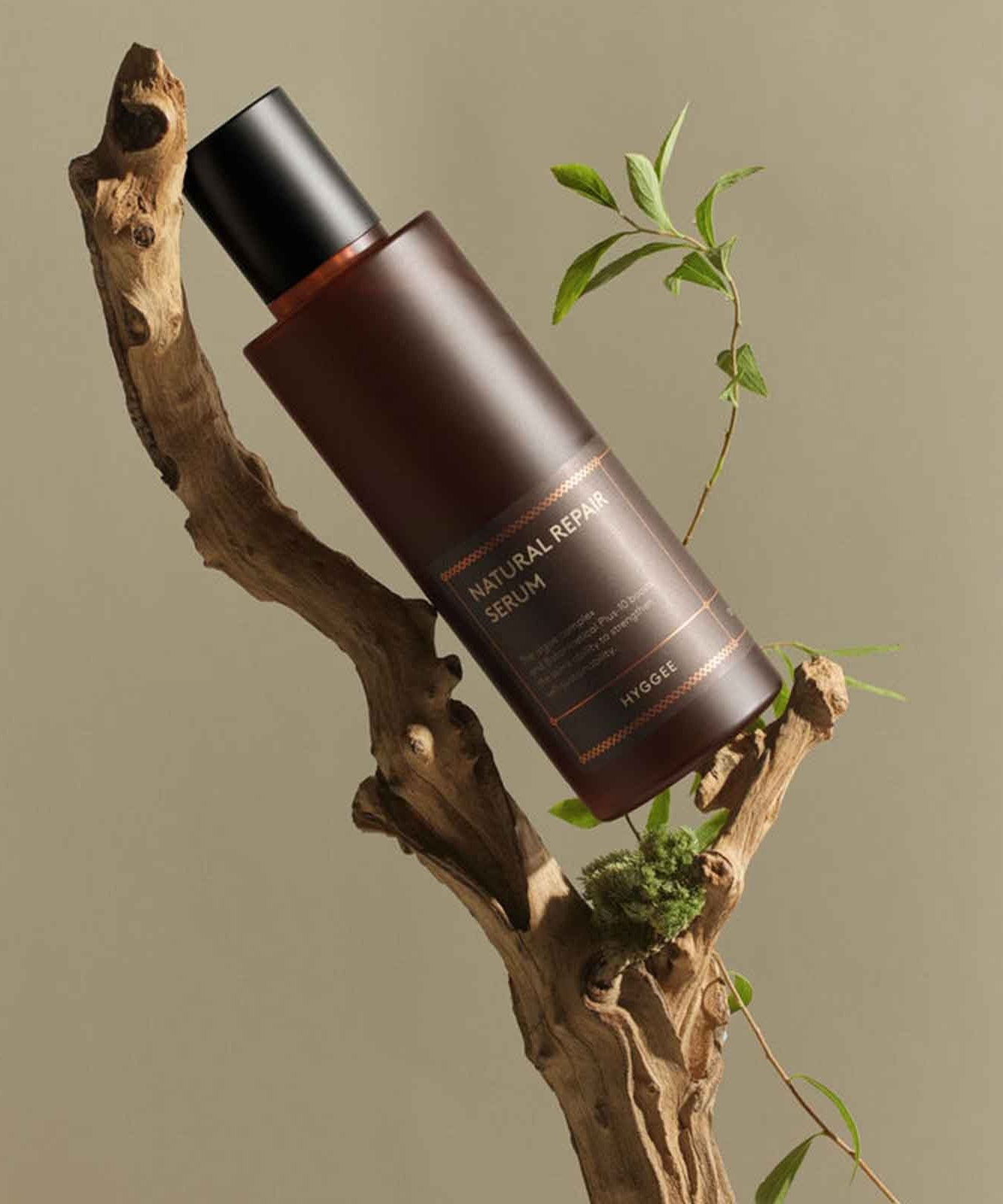 HYGGEE Natural Repair Serum 120ml, flacon sur branche naturelle avec feuilles et ambiance soin, marque HYGGEE
