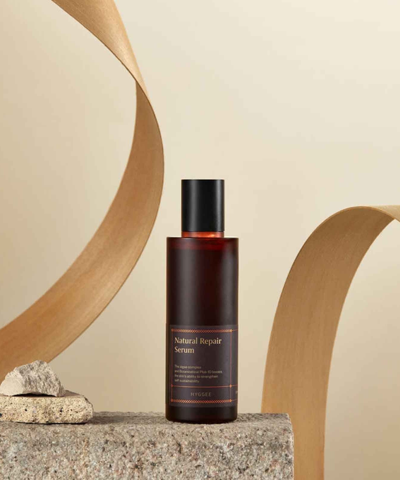 HYGGEE Natural Repair Serum 120ml de HYGGEE, flacon sur pierre avec décor bois beige, contexte beauté naturel