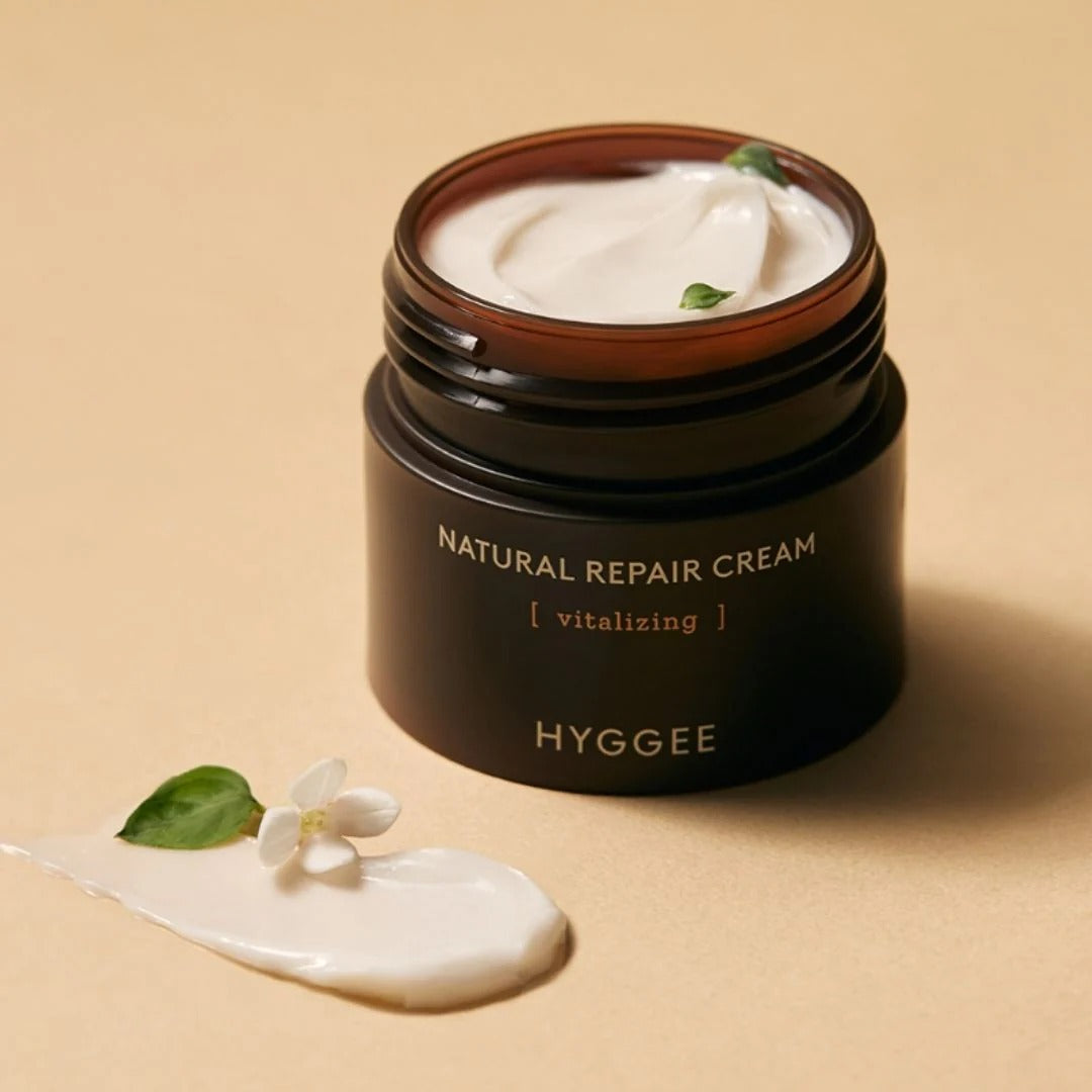 HYGGEE Nature Repair Cream 50ml, pot de crème naturelle sur fond beige, texture blanche et feuilles vertes, marque HYGGEE