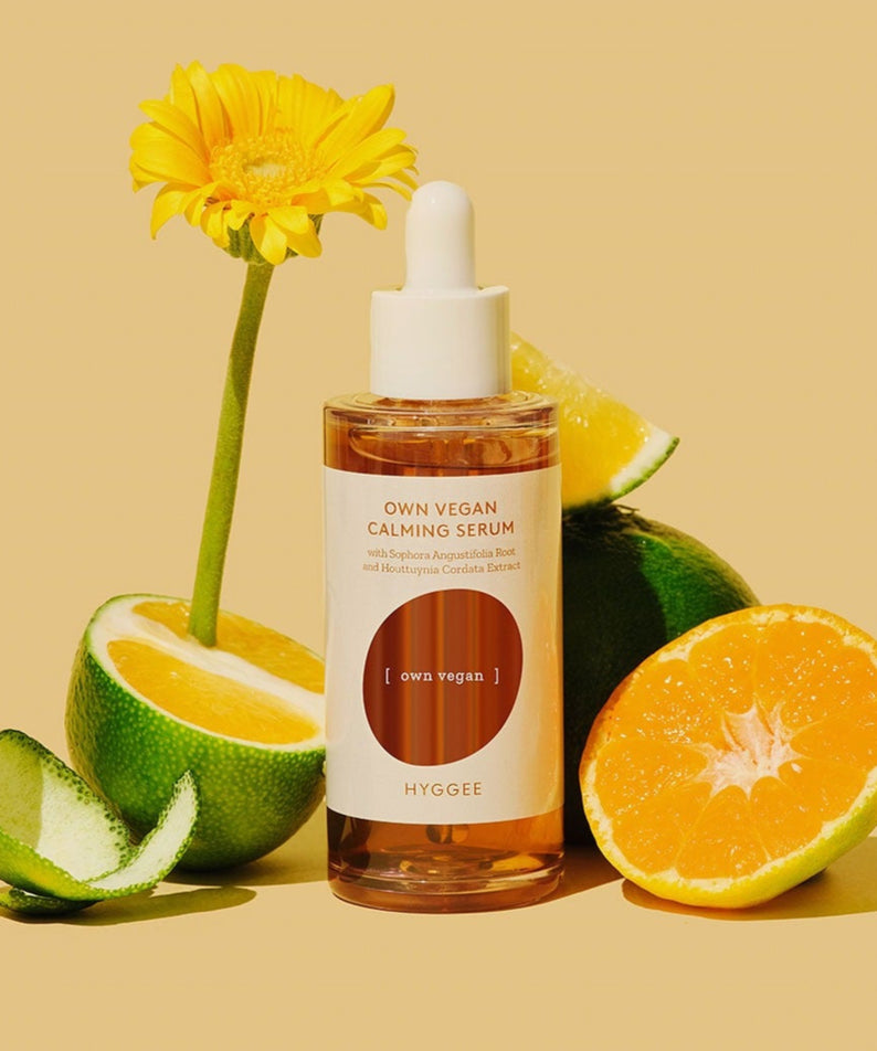 HYGGEE Own Vegan Calming Serum 50ml : flacon sur fond jaune, avec fleurs et agrumes, contexte beauté apaisante