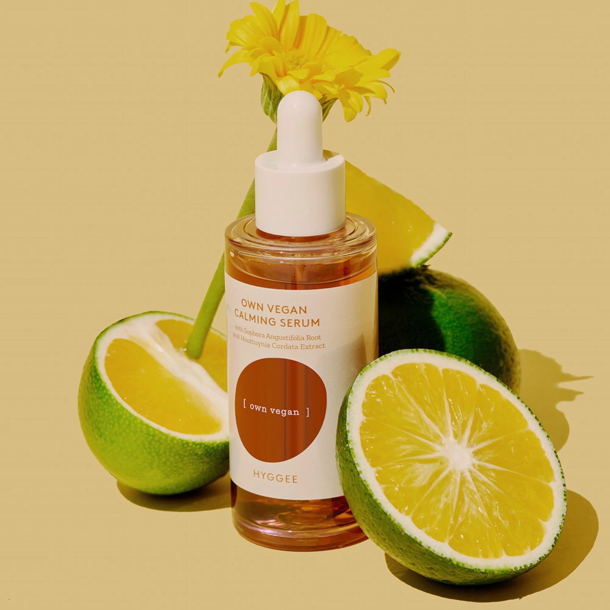HYGGEE Own Vegan Calming Serum 50ml, flacon sur fond beige, fleurs et citrons en contexte cosmétique apaisant