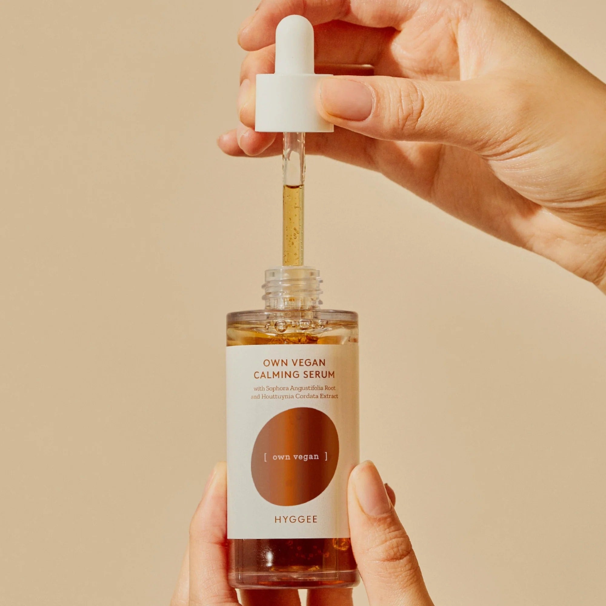HYGGEE Own Vegan Calming Serum 50ml de la marque HYGGEE, main tenant le sérum goutte à goutte, contexte beauté apaisante