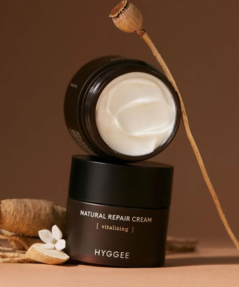 Crème HYGGEE Nature Repair Cream 50ml, pot ouvert avec texture crémeuse, ingrédients naturels en arrière-plan, soin réparateur visage.