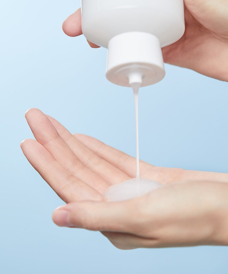 ILLIYOON Ceramide Ato Moisturizing Skin 250ml : tube crème appliquée sur mains, fond bleu, mise en scène peau hydratée