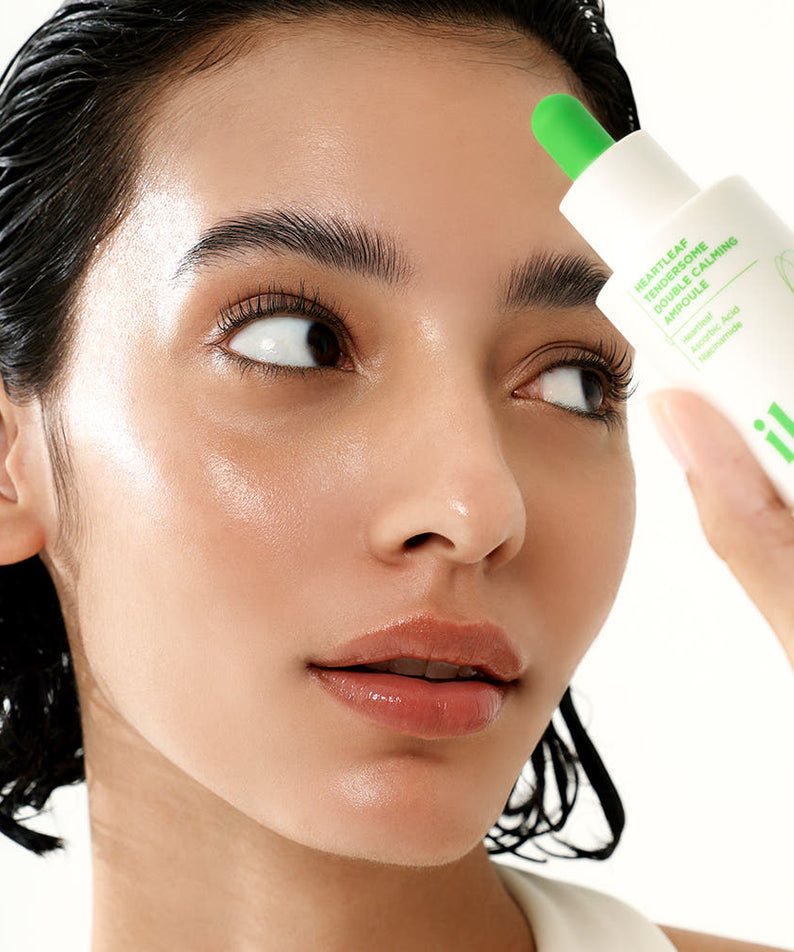 Femme tenant le produit ILSO Eoseongcho Tenderjom Double Calming Ampoule 30ml pour soin de la peau au teint éclatant.