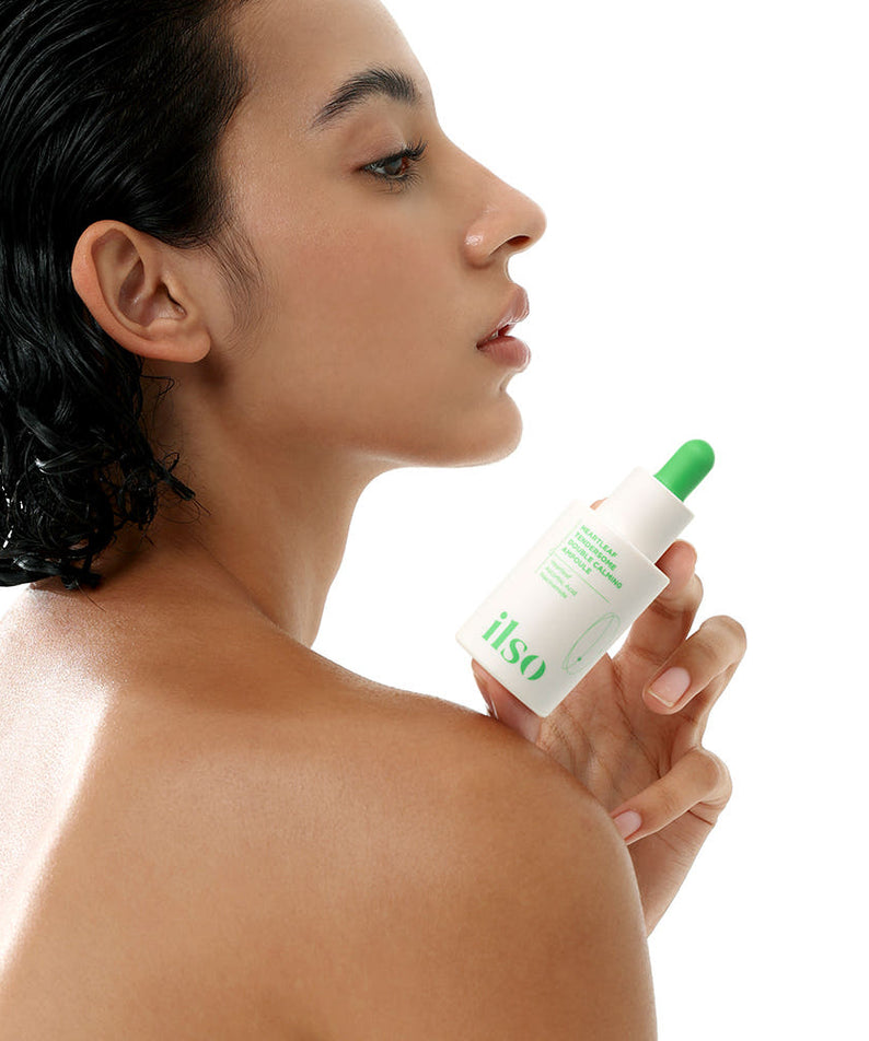 Modèle tenant ILSO Eoseongcho Tenderjom Double Calming Ampoule 30ml, sérum apaisant pour la peau, vue de profil.