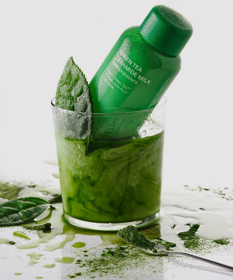 INNISFREE Green Tea Ceramide Milk Essence 160ml en flacon vert, entouré de feuilles de thé vert et splash, sur fond blanc