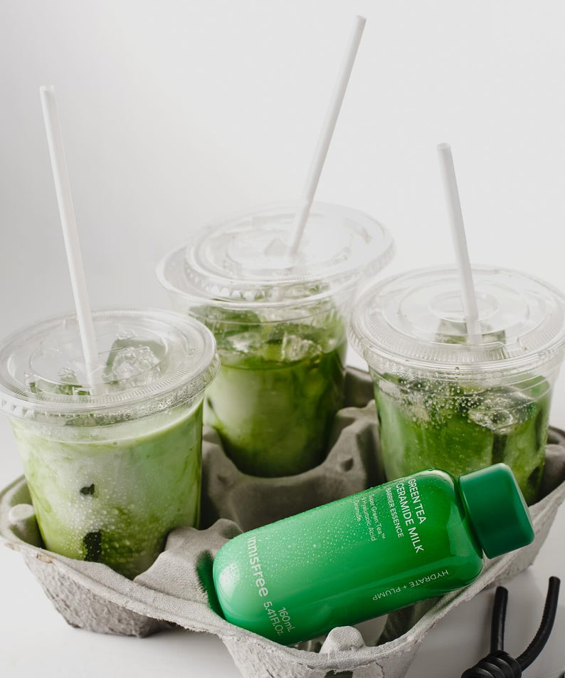 INNISFREE Green Tea Ceramide Milk Essence 160ml, flacon vert sur plateau avec boissons matcha, style promo en studio