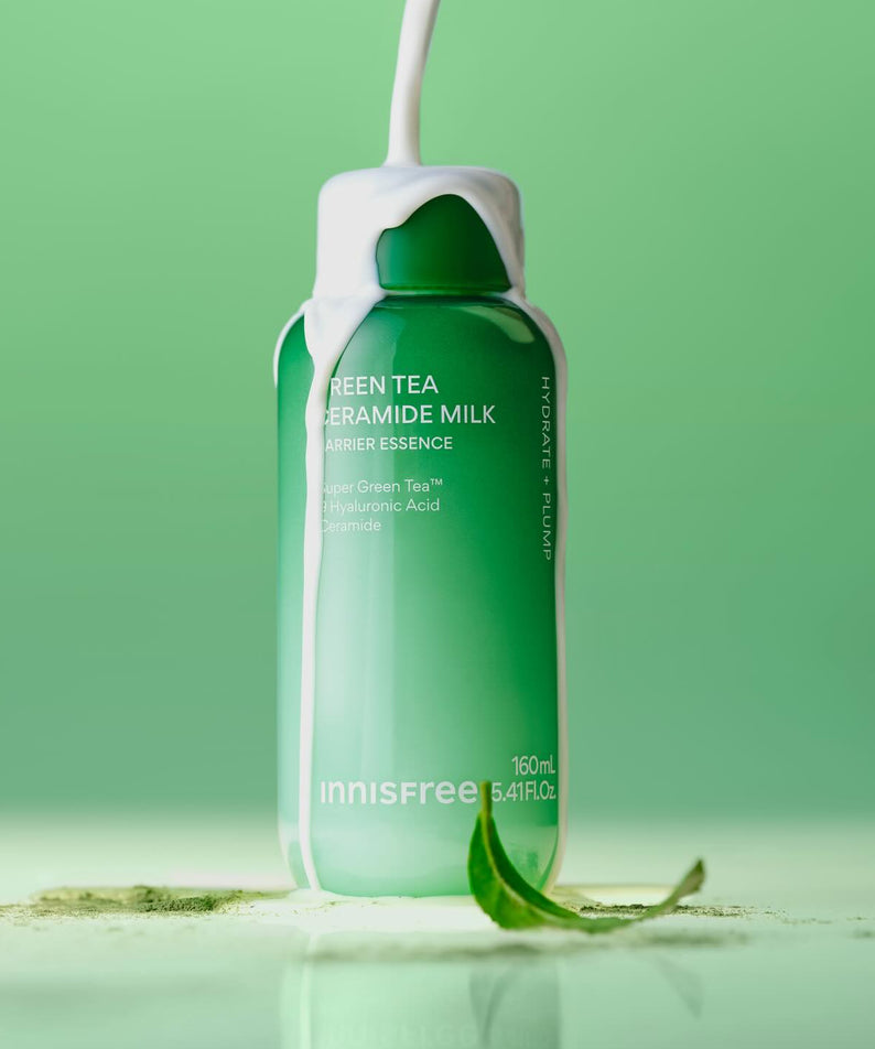 INNISFREE Green Tea Ceramide Milk Essence 160ml, bouteille en verre verte sur fond vert, feuilles de thé en contexte visuel.