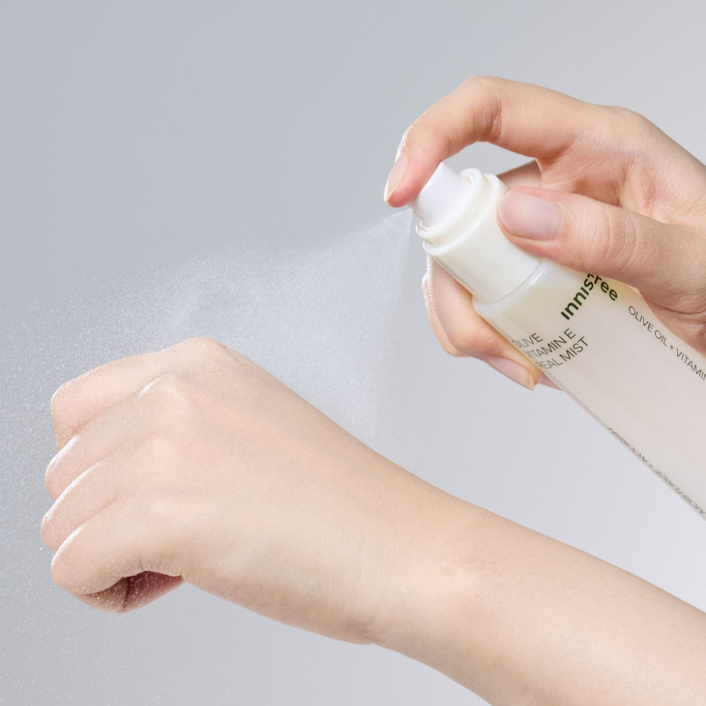 INNISFREE Olive Vitamin E Real Oil Mist 75ml, main vaporisant l’huile sur la peau, visuel beauté INNISFREE sur fond clair.