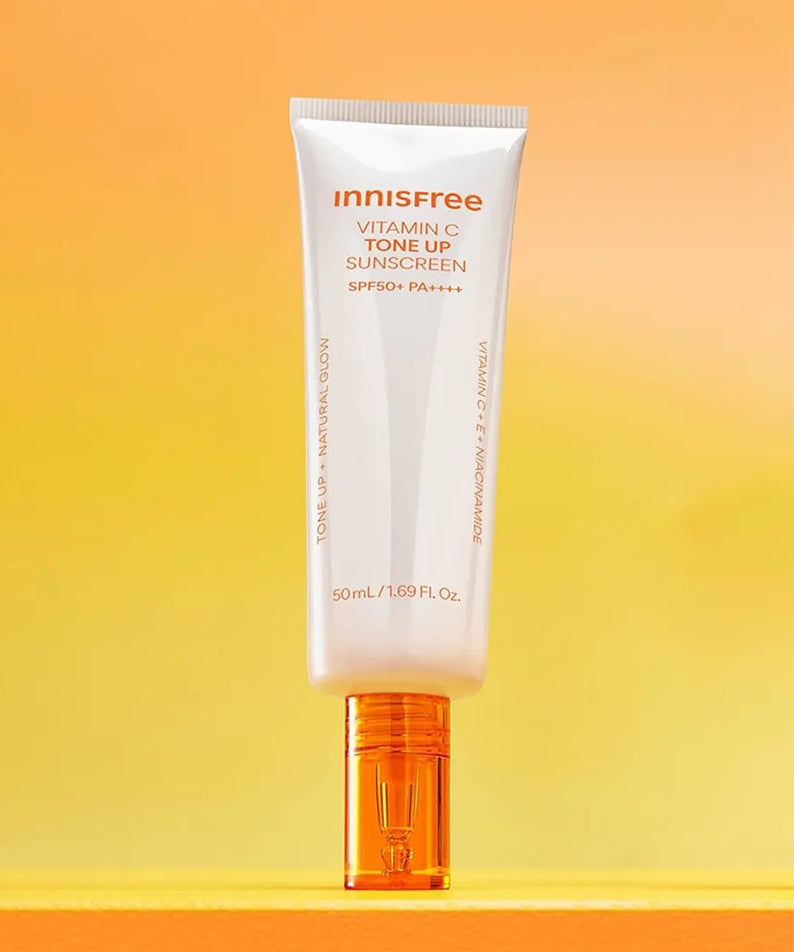 INNISFREE Vita C Spot Tone Up Sunscreen SPF50+/PA++++ 50ml, tube crème solaire sur fond jaune ensoleillé.