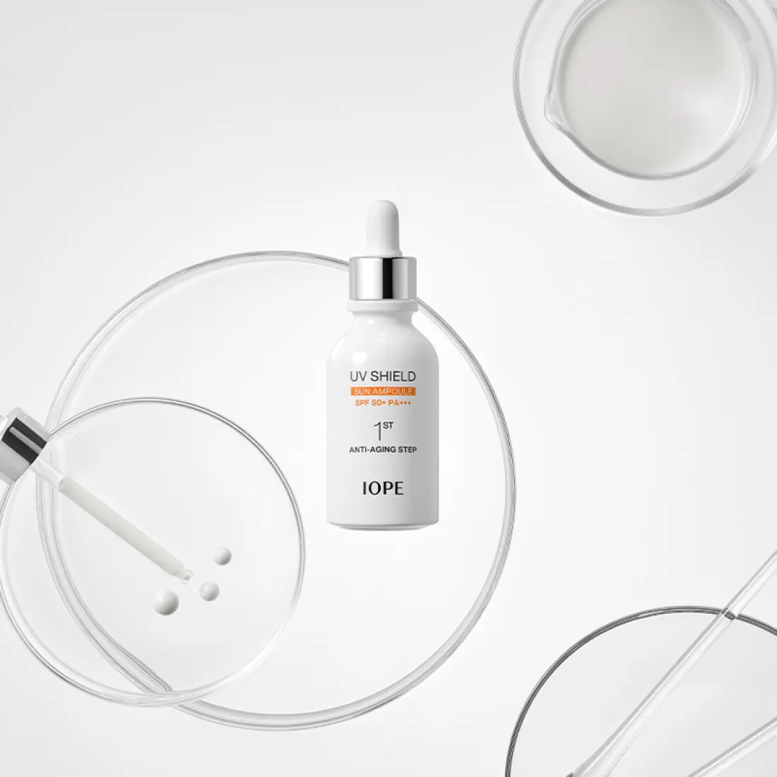 IOPE UV Sheild Sun Ampoule SPF 50+PA+++ 40ml, flacon IOPE sur fond blanc avec éléments UV, flèches et gouttes.