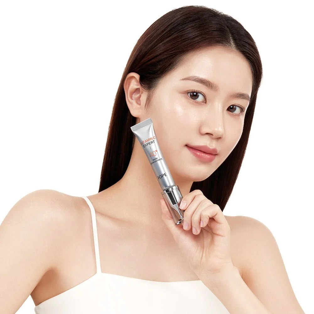 Jeune femme sur fond clair tenant le IOPE Vitamin C Expert 40% Mask Concentrate 15g de la marque IOPE