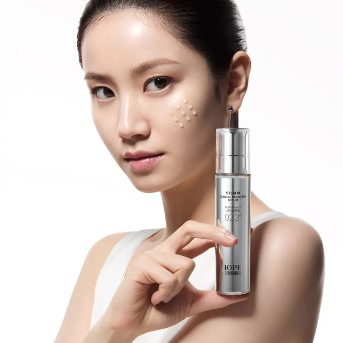 IOPE XMD Stem3 Clinic Recoery Serum 50ml : sérum présenté sur une femme, flacon sur fond clair, marque IOPE.