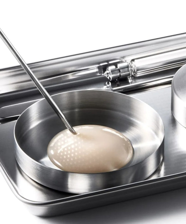 IOPE XMD Stem3 Clinic Recoery Serum 50ml en laboratoire, texture luxueuse et innovation skincare sur plateau en acier.