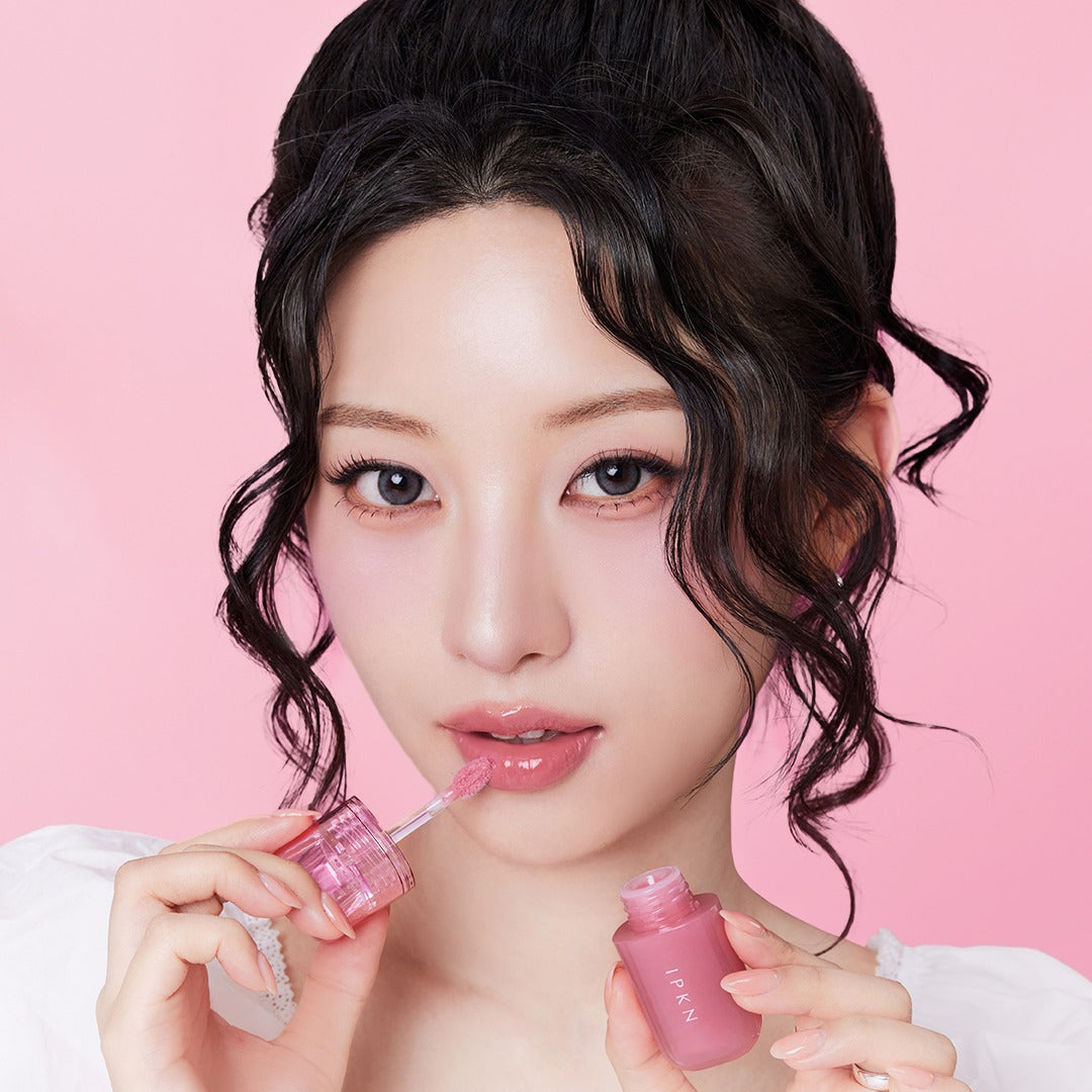 Portrait maquillage sur fond rose : IPKN Bubble Jam Gloss de la marque IPKN, flacons de gloss brillants en gros plan.