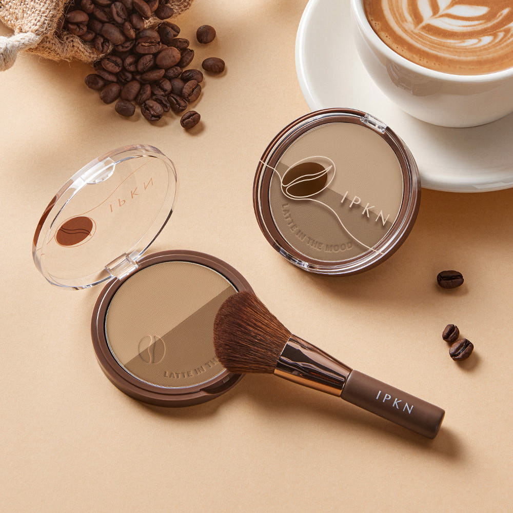 IPKN  Latte in the Mood Contouring de la marque IPKN, poudre et pinceau, scène café avec grains de café.
