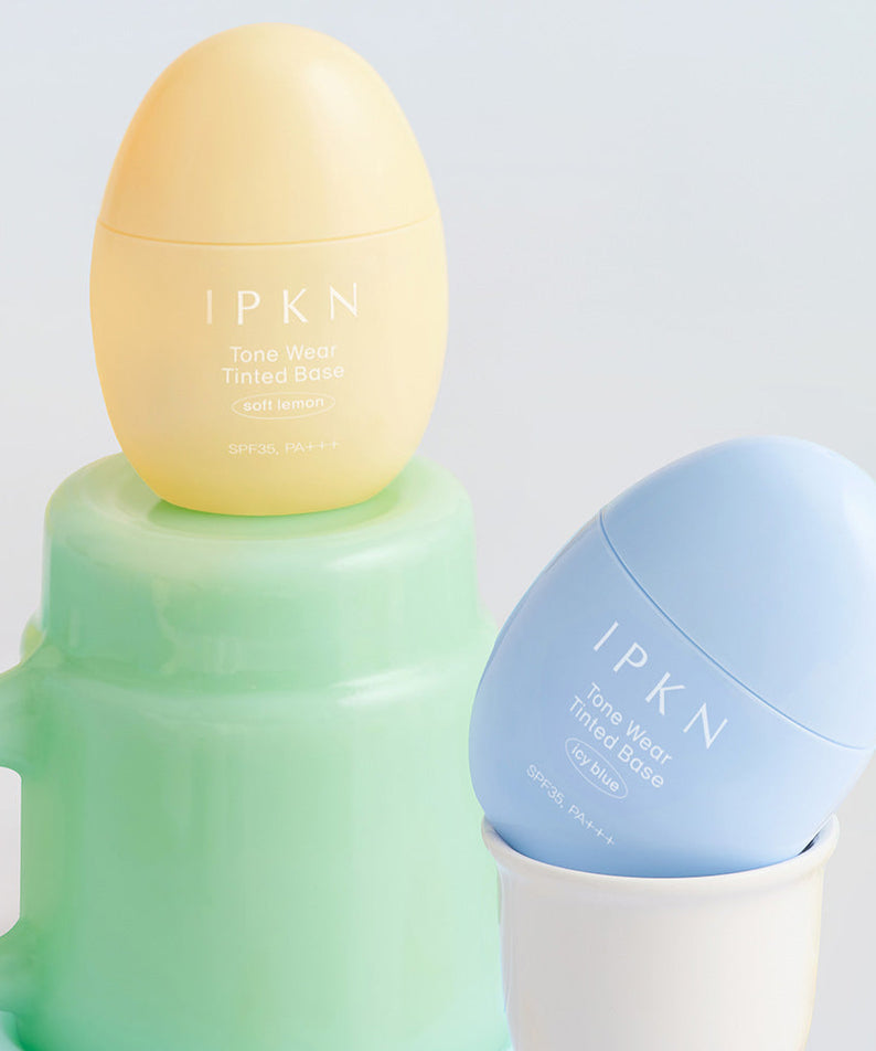 Produits cosmétiques IPKN Tone Wear Tinted Base en jaune et bleu pour un teint lumineux et uniforme.
