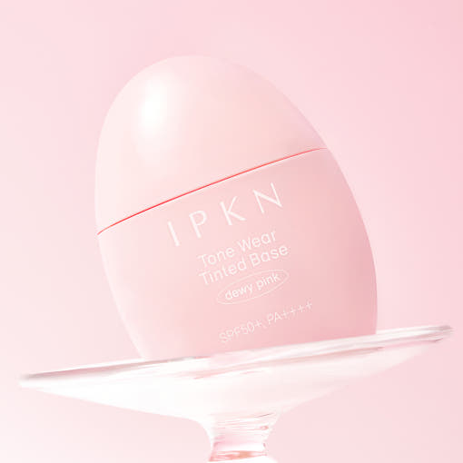 IPKN  Tonewear Tinted Tone-Up Base 40ml SPF50+ PA++++, packaging rose sur support, mise en scène beauté en studio