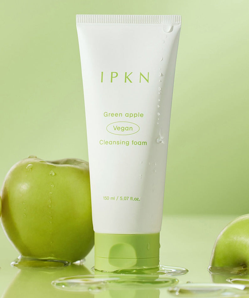 IPKN Green Apple Vegan Cleansing Foam 150ml avec flacons et pommes vertes en arrière-plan, produit de soin visage.