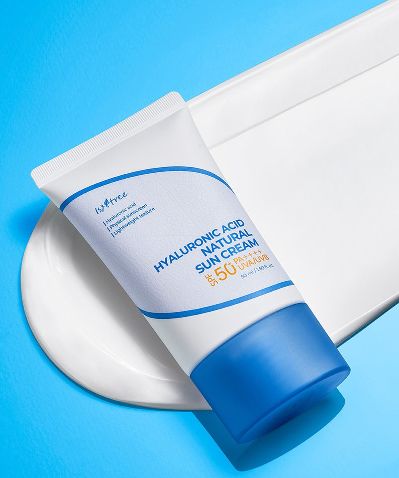 ISNTREE Hyaluronic Acid Natural Sunscreen 50ml, crème solaire hydratante, tube blanc et bleu sur fond ciel, photo produit.