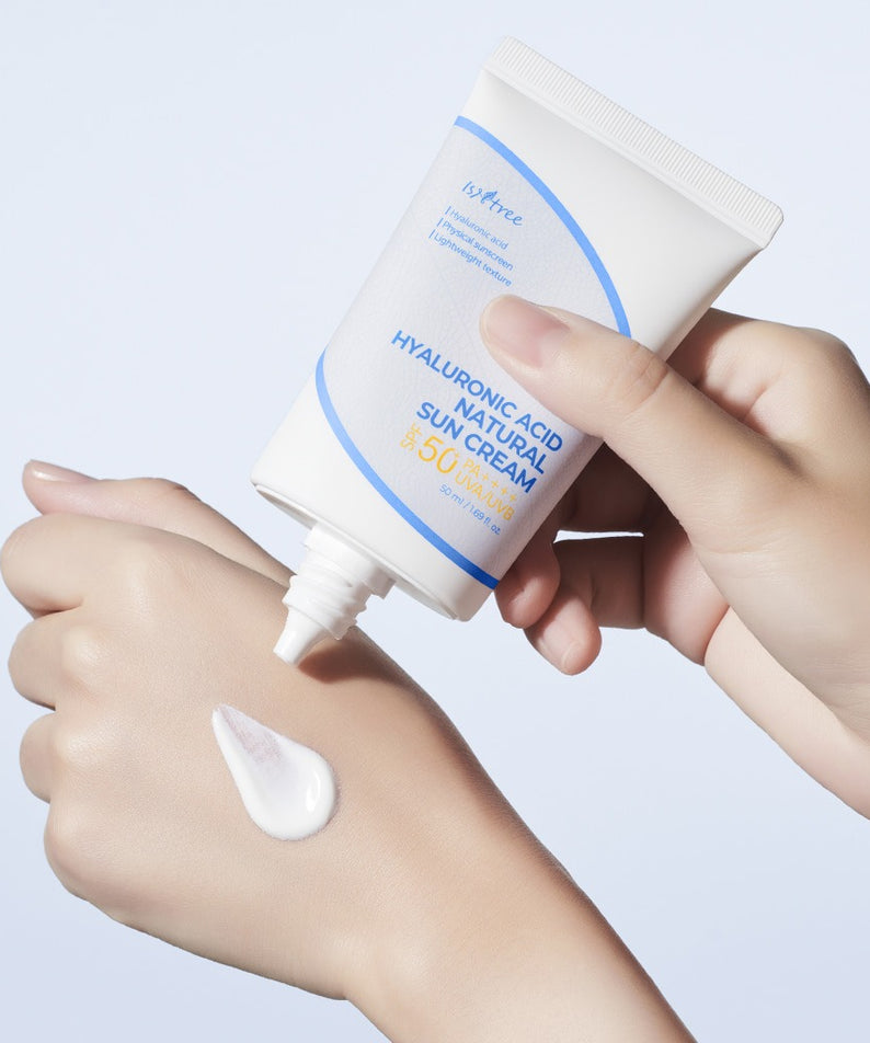 ISNTREE  Hyaluronic Acid Natural Sunscreen 50ml, tube et crème appliquée sur la main, mains en gros plan, fond clair