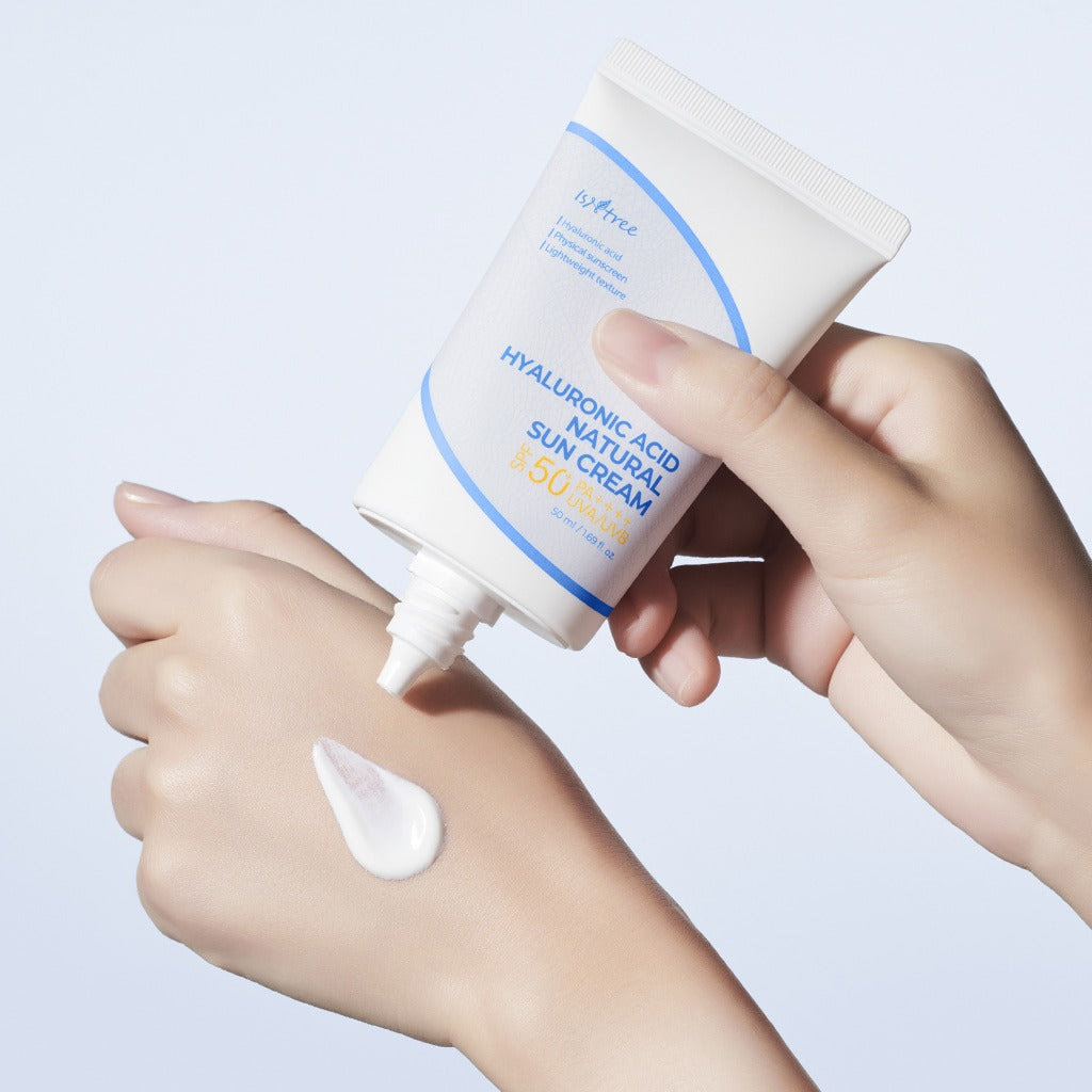 ISNTREE  Hyaluronic Acid Natural Sunscreen 50ml, tube et crème appliquée sur la main, mains en gros plan, fond clair