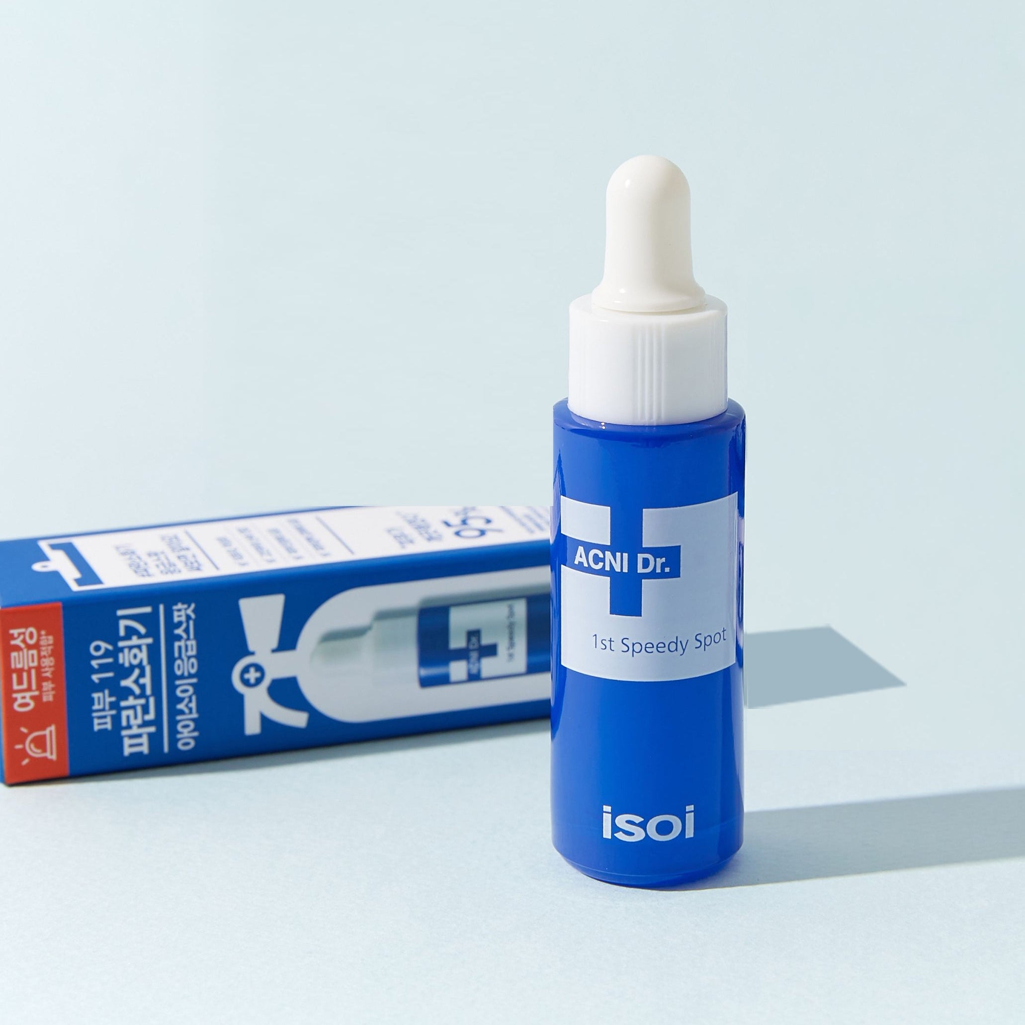 ISOI ACNI Dr. 1st Speedy Spot (14ml) de la marque ISOI, sérum anti-imperfections sur fond bleu clair avec boîte