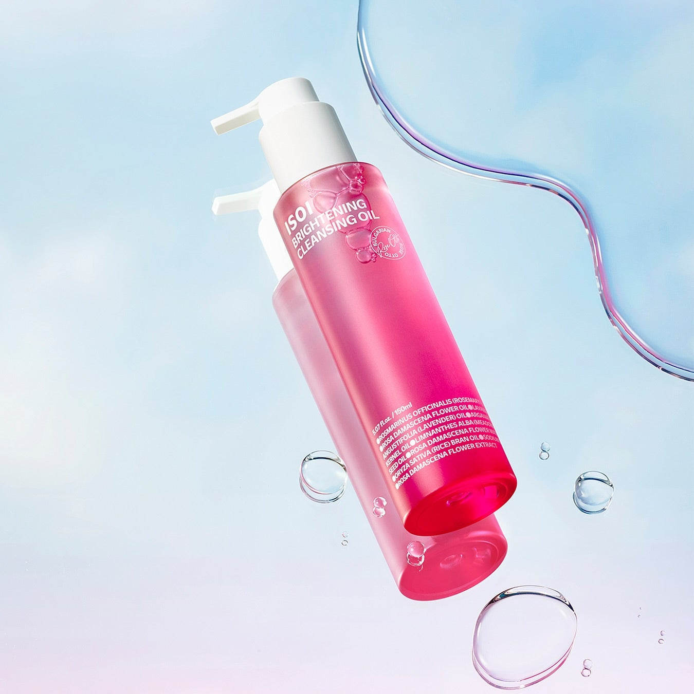 ISOI Brightening Cleansing Oil 150ml, flacon rose ISOI sur fond bleu clair, gouttes d’eau et esthétique skincare