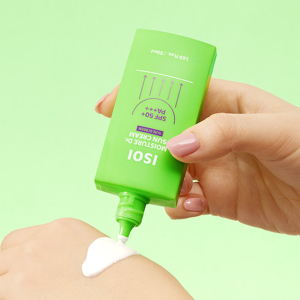 Main tenant ISOI Moisture Doctor Sun Cream SPF50+PA+++ 50ml de la marque ISOI, crème solaire sur peau, fond vert