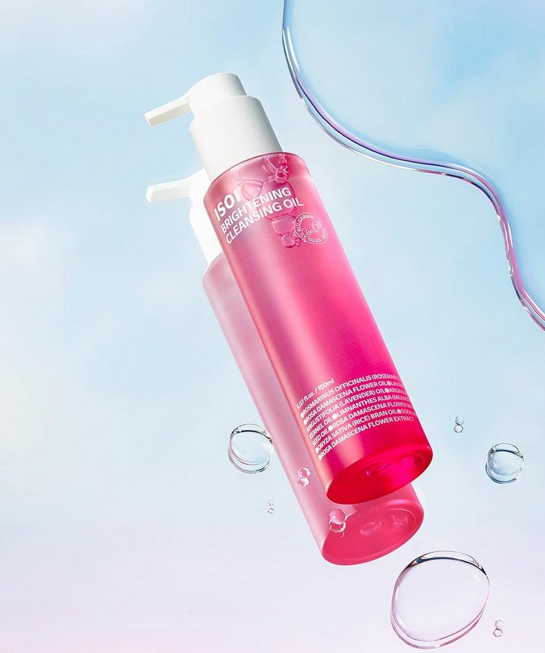 ISOI Brightening Cleansing Oil 150ml en bouteille rose sur fond bleu ciel avec gouttes d'eau transparentes.