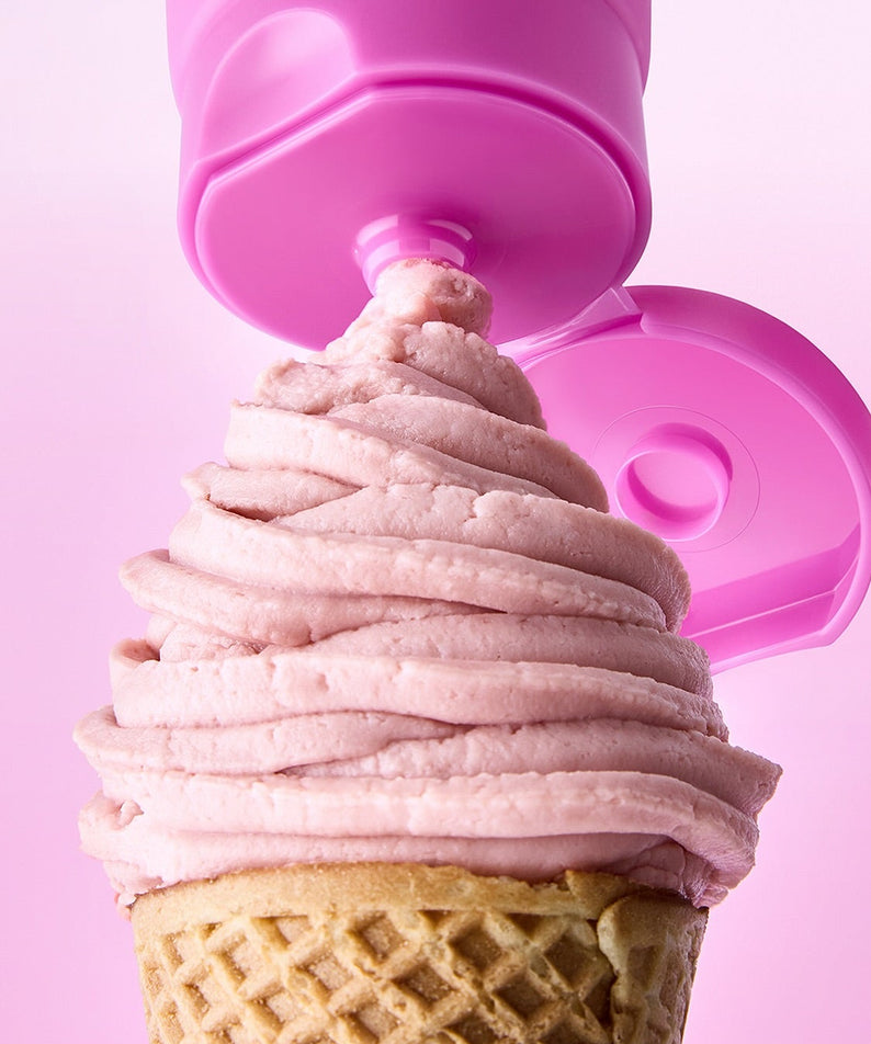 Crème glacée rose en spirale sur un cornet avec un bouchon rose en arrière-plan.