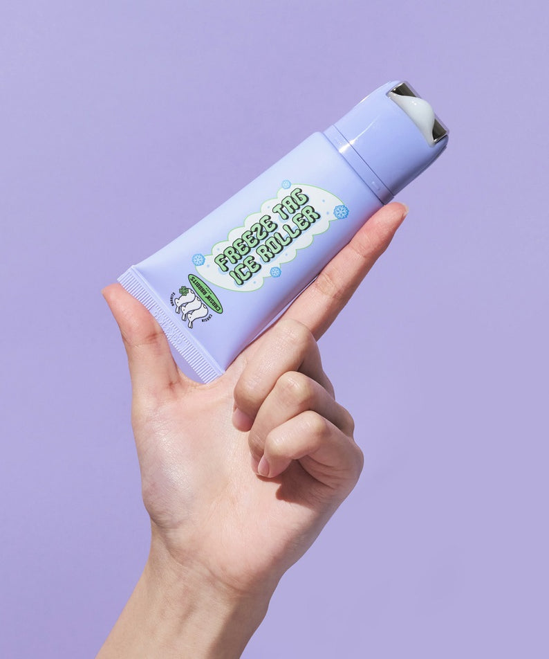 Main tenant le IT'S SKIN Freeze Tag Ice Roller dans un fond violet, soin rafraîchissant pour la peau.