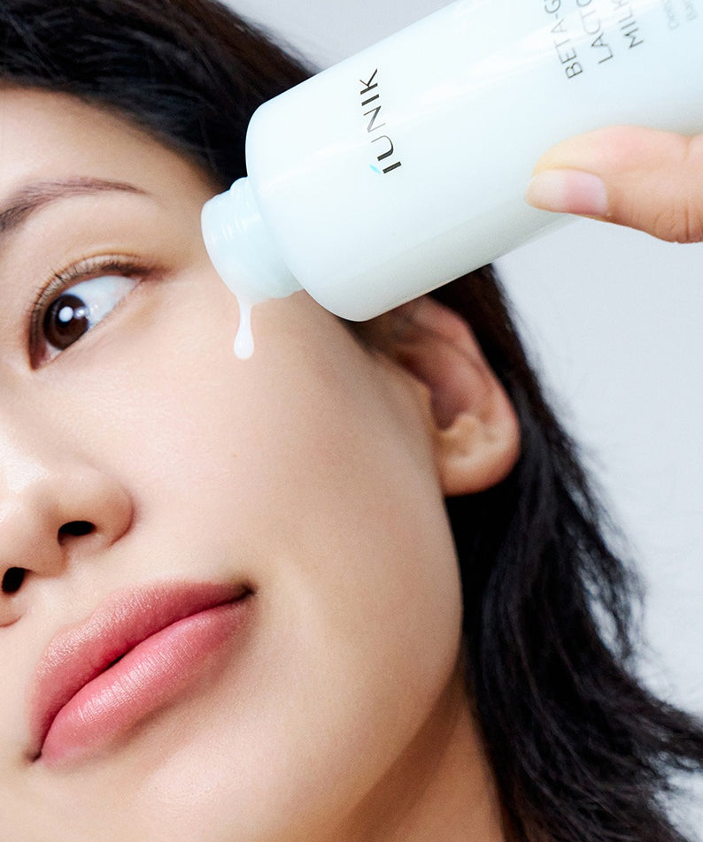 IUNIK Beta Glucan Lactobarrier Milk Essence 200ml, flacon appliqué sur le visage d’une femme, marque IUNIK, soin beauté