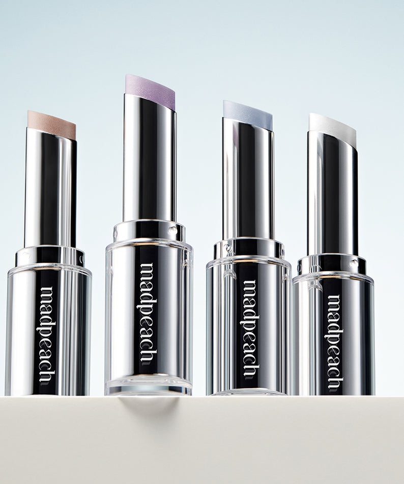 Quatre sticks en surbrillance IVI MAD PEACH Milky Way Highlighter Stick posés côte à côte sur une surface blanche, différents tons irisés.