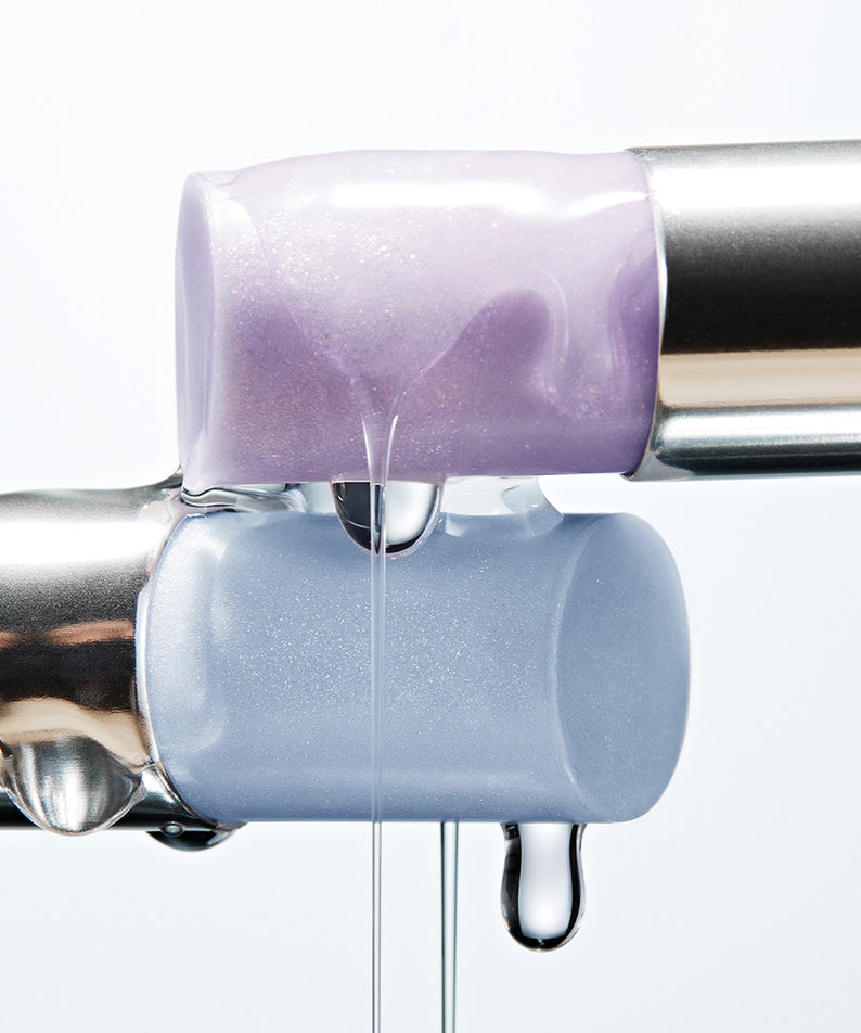 Deux sticks de highlighter violets métalliques avec texture crémeuse, parfaits pour brillance et éclat.